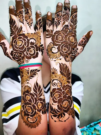 A happy client showing off her beautiful rose-themed mehndi.