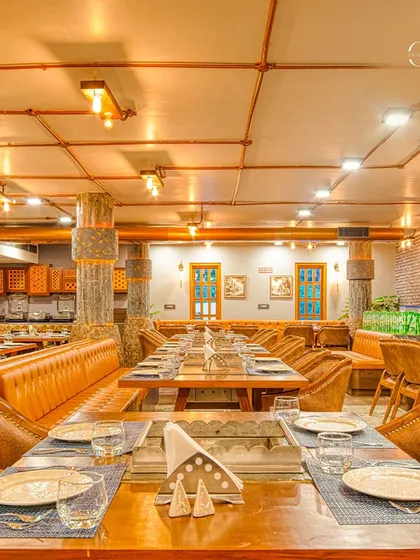 This long shot of the restaurant highlights the community-style dining tables and the custom-designed pillars with metal detailing. The layout is perfect for accommodating large groups while maintaining an intimate feel.