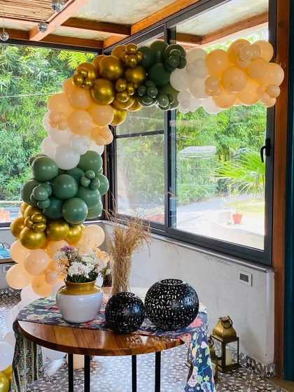A full view of the olive green and peach balloon arch over a decorated table.