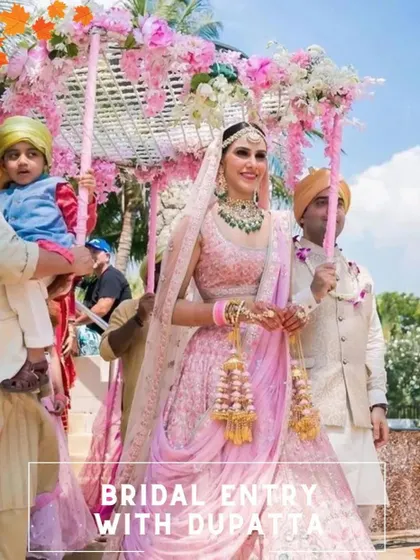 A beautiful bridal entry under a 'phoolon ki chaadar' made of a pink dupatta and decorated with flowers, held by her loved ones.