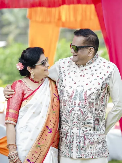 A lovely candid moment between the parents of the bride. Her simple updo with a flower and her fresh makeup look are perfect for the festive occasion.