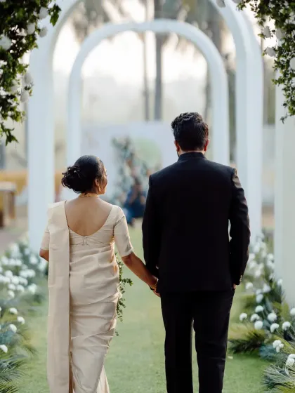 A modern and minimalist wedding aisle design. The clean white arches create a beautiful, repeating pattern that guides the eye towards the main stage, perfect for a contemporary celebration.