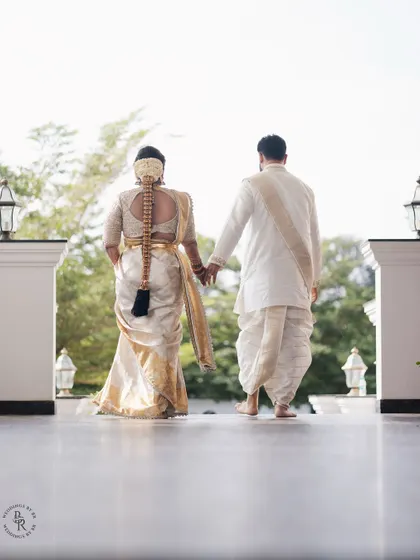 The couple walks away hand-in-hand, showcasing the bride's beautiful traditional hairstyle and the elegance of their matching outfits.