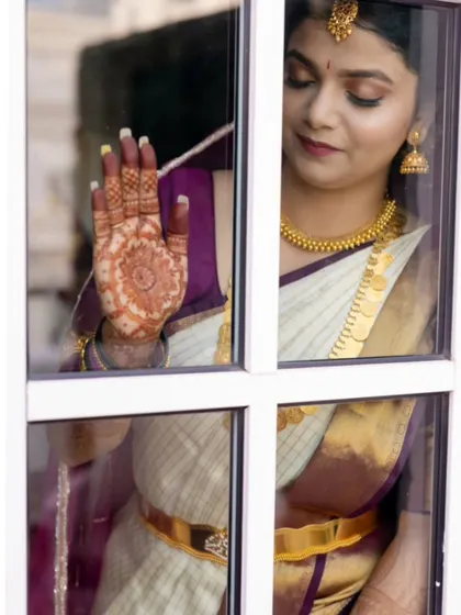 A poetic shot of a bride, her henna-adorned hand against a window pane. The rich stain of the mandala design is beautifully captured in this artistic photo.
