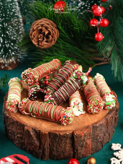 Another angle of the festive chocolate rolls, stacked on a rustic wooden log for a warm, woodland Christmas vibe.