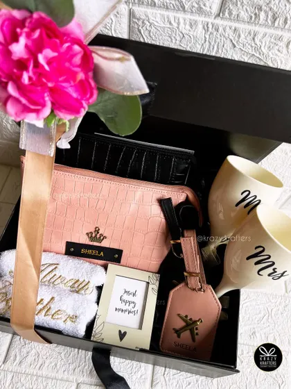 The complete couple's travel hamper, beautifully presented with a large pink flower and ribbon on a sleek black box.
