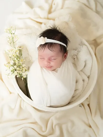 A peaceful newborn portrait, styled with delicate baby's breath flowers and soft, cream-coloured fabrics for a pure and angelic look.