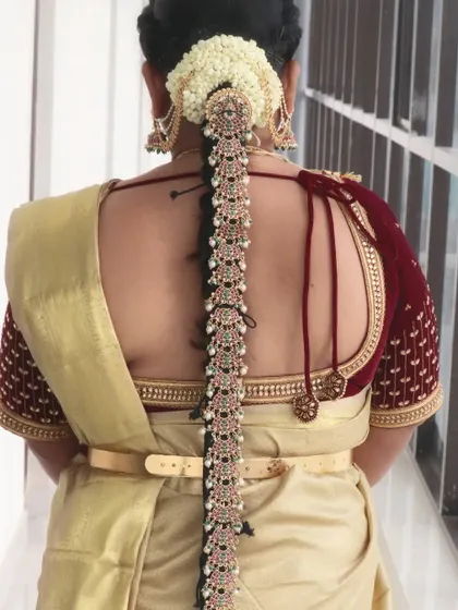 A classic South Indian bridal hairstyle. This long braid is adorned with beautiful kemp stone jewelry and fresh jasmine, a timeless choice for any traditional bride.