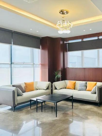 This waiting area for an MD's room features contemporary sofas with clean lines and pops of color from the throw pillows. The recessed ceiling with a modern chandelier creates a sophisticated and well-lit space.