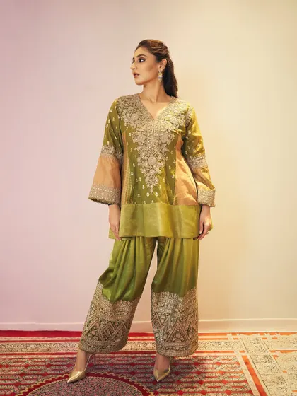 A confident pose showing the complete outfit. The combination of the structured peplum top and flowing pants creates a balanced and elegant silhouette, perfect for a formal occasion.