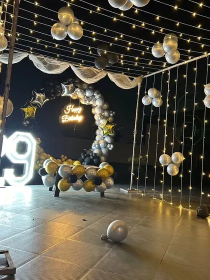 I love creating stylish outdoor celebrations, like this 29th birthday setup. The space is defined by a curtain of fairy lights, a custom neon sign, and a modern balloon arch, complemented by a large light-up marquee number to make the occasion feel grand.