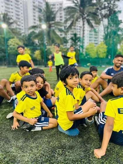 Young players sitting and listening to their coach. The camaraderie and shared learning experience are invaluable.