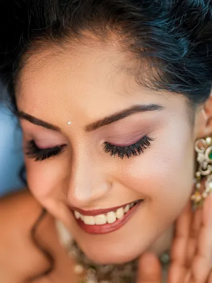 A joyful close-up focusing on the model's smile and flawless makeup, particularly the eyelashes. This shows our ability to capture beauty details.