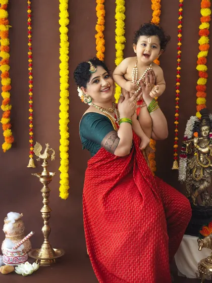 A moment of pure joy as a mother lifts her laughing baby Krishna in the air.