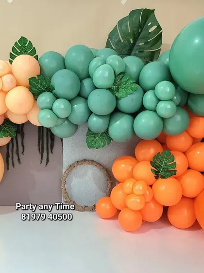 A beautiful pastel balloon arrangement with tropical leaves, perfect for a cake smash or baby photoshoot.