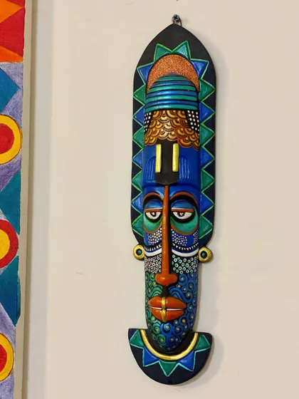 A full, direct view of the repainted mask, showcasing the geometric patterns and the sad yet colorful expression.