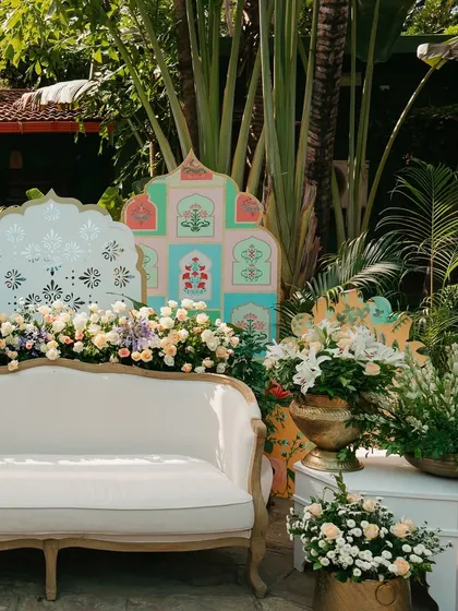 A beautiful seating area for the couple at their Mehendi, with a pastel-colored backdrop and lush florals.