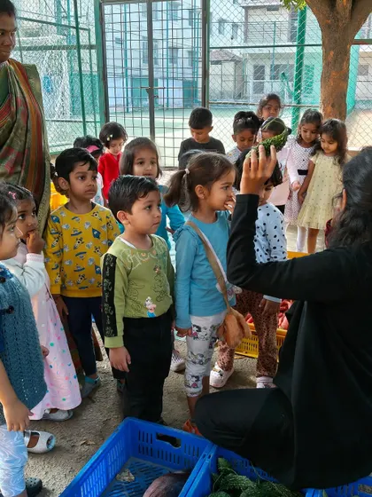 A teacher shows the children a watermelon, letting them feel its texture and weight. These sensory explorations are a core part of our learning philosophy.