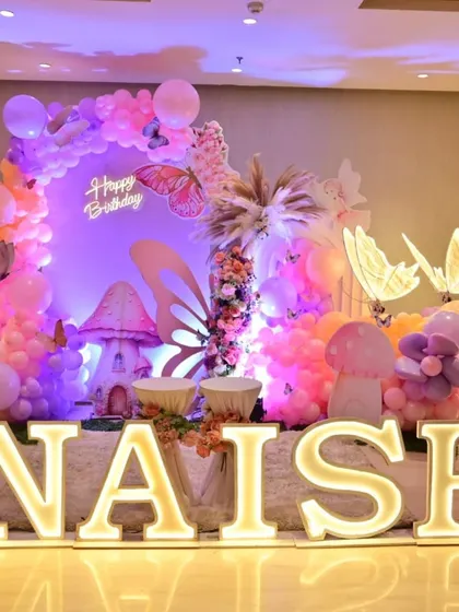 Large, illuminated marquee letters spelling out the birthday girl's name, 'ANAISHA', add a personalized and show-stopping element to the butterfly theme decor.