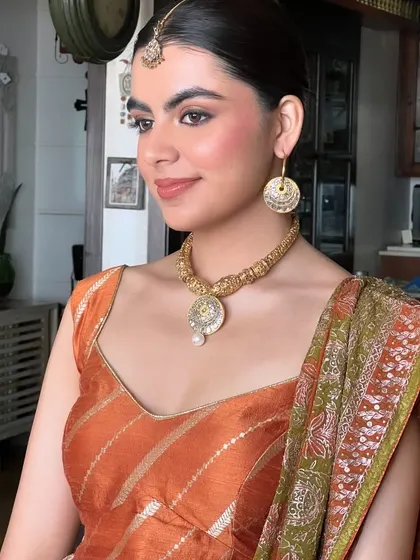 A close-up of the soft, mehendi-inspired makeup. The look is warm and elegant, with a focus on clean skin and defined features.