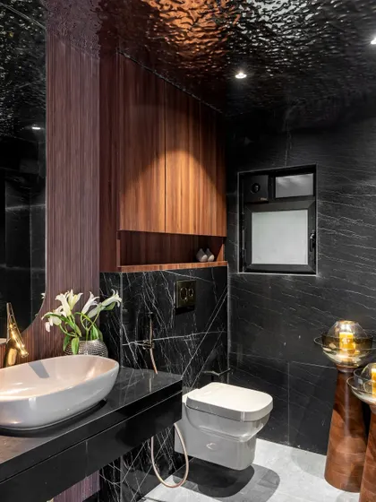 A different perspective of the dark powder room, showing the vessel sink and the unique floor-standing candle holders. The design plays with light and shadow to create a sophisticated and memorable experience.