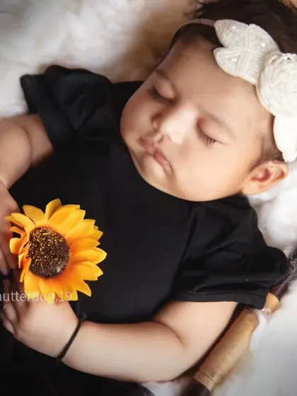 A sweet close-up of a sleeping newborn holding a single sunflower, a simple and beautiful portrait.