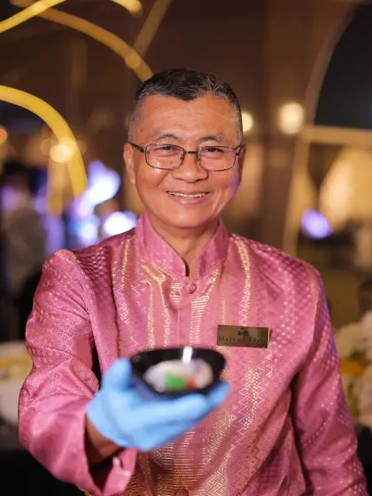 A welcoming gesture from one of our international chefs. He proudly presents a small bowl, offering a taste of the authentic cuisine he has prepared.