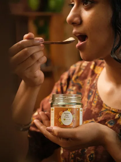 A lifestyle shot of a woman enjoying a spoonful of a product, with the jar held in her hand. This creates a personal and relatable connection between the customer and the product.