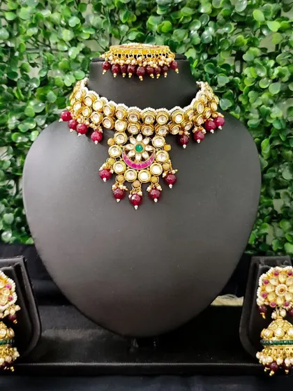 This vibrant rental set features a kundan choker with rich red bead drops. The matching earrings have a touch of green, making it a perfect match for traditional bridal wear.