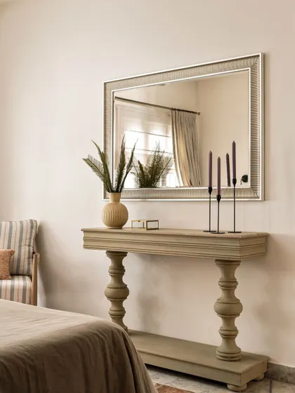 A distressed-finish console table and an ornate mirror add to the vintage charm of the master bedroom. These carefully selected pieces contribute to the room's story, making it feel curated over time.