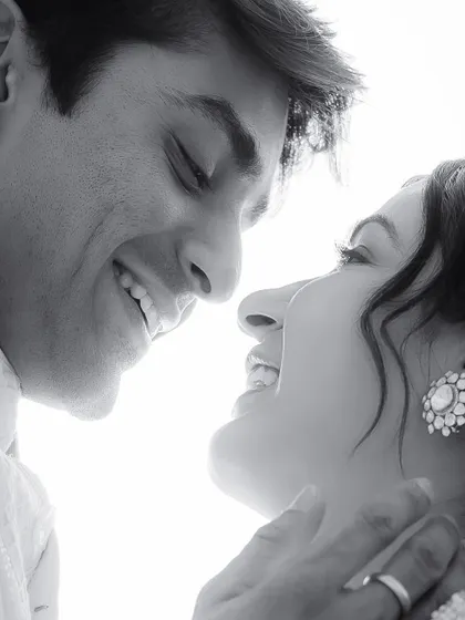 A high-contrast black and white portrait of Radheeka and Pulkit, capturing a moment of pure joy and connection.