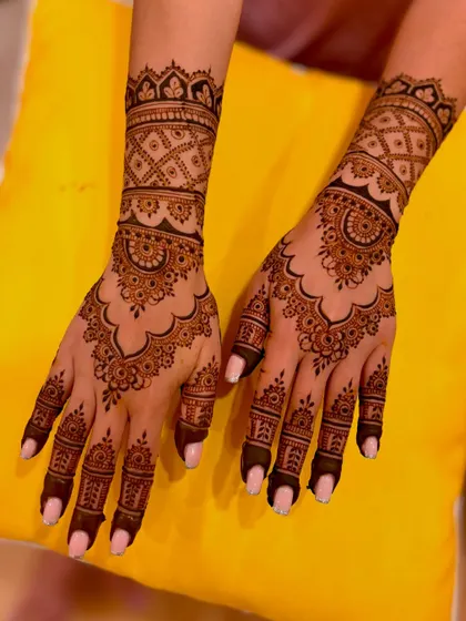A classic engagement mehendi design with wrist-length coverage, featuring scalloped edges and detailed patterns.