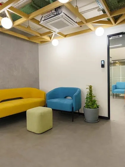 This waiting or breakout area uses bold primary colors in its furniture to create a playful and welcoming atmosphere. A potted snake plant adds a touch of green and improves indoor air quality.