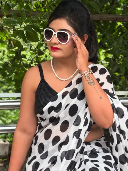 A full retro glam look. This vintage style features a polka dot saree, classic winged eyeliner, a bold red lip, and oversized white sunglasses.