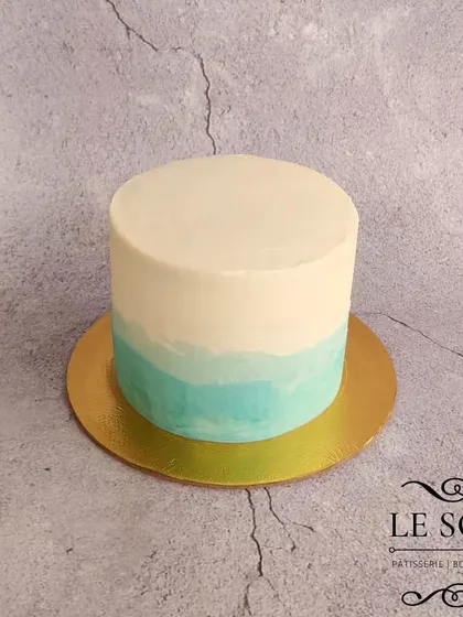 A simple and minimalist smash cake, perfect for a baby's first photos. This one-pound classic vanilla cake has a clean white and blue ombre finish.