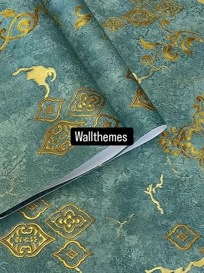 A close-up of a teal wallpaper with a distressed texture and a gold damask-inspired pattern.