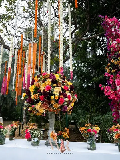 A console table overflowing with a riot of colorful flowers. This arrangement, set against a backdrop of hanging marigold and tuberose garlands, was a celebration of color, texture, and fragrance.
