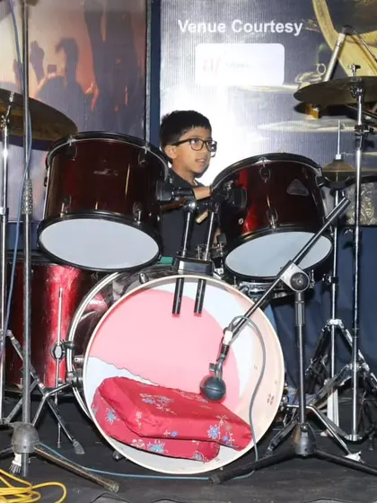 A young student at his drum kit, ready to perform 'Bones'.