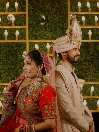 A close-up portrait of the bride and groom in a back-to-back pose. This shot focuses on their expressions and the intricate details of their wedding outfits and jewelry.