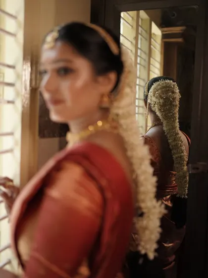 This artistic shot captures the details of the traditional bridal hairstyle, adorned with a full strand of fresh jasmine flowers, known as a gajra.