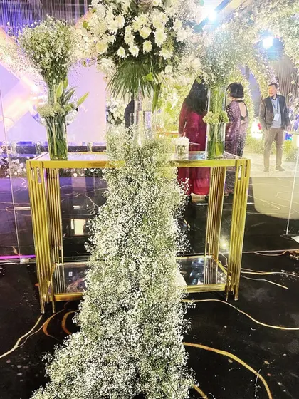 A decor detail from an engagement, where a cascade of baby's breath flows from a tall gold table, blending modern design with soft, romantic florals.