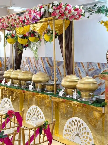 The catering and buffet setup at our banquet hall. The counter is decorated with flowers and elegant chafing dishes are laid out for the meal.