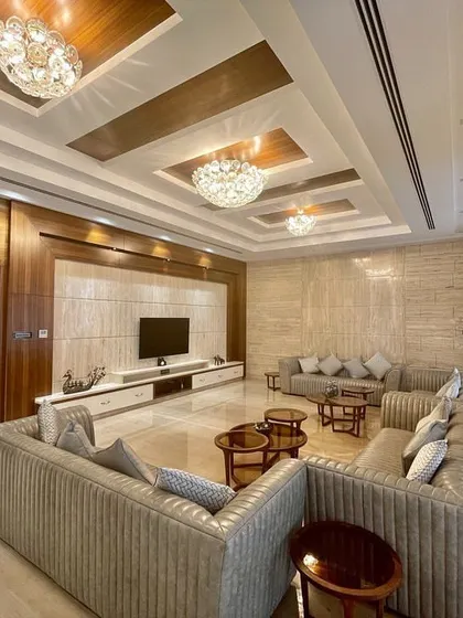 This family living room combines plush, comfortable seating with elegant materials like marble and wood, complete with a large media unit and ambient ceiling lighting.
