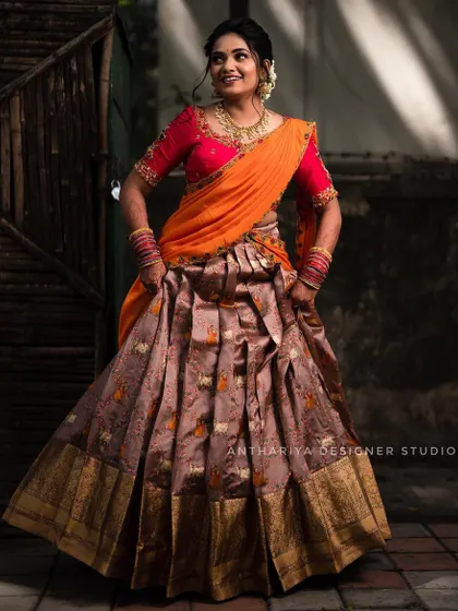 The same orange and brown Langa Voni, captured in a joyful, twirling motion that shows off the skirt's pleats.