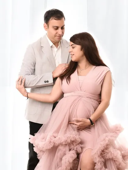 A romantic portrait of a couple dressed in formal wear. The soft pink gown and light grey blazer create a beautifully coordinated and elegant look.