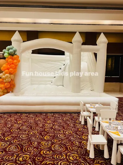 The 4-in-1 white bouncy castle decorated with a balloon garland, ready for an indoor birthday celebration.