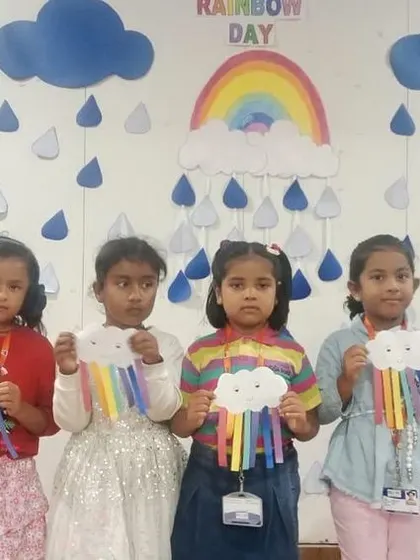 A group of girls proudly holds up their rainbow crafts, each one unique and colorful.
