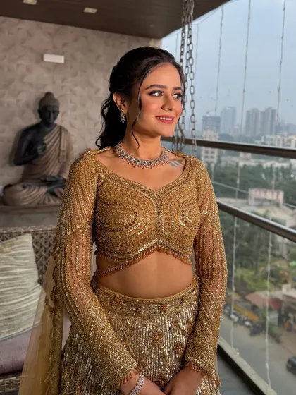 A beautiful shot of the client by the window. The natural light enhances the golden tones in her makeup and the sparkle of her outfit.