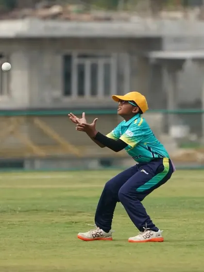 A fielder focuses on taking a high catch, a skill that requires concentration and practice.