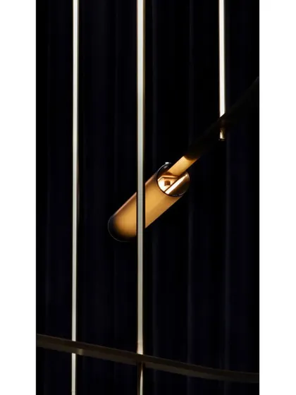A close-up detail of a single Volant light, showing the textured glass tube and the delicate brass clip that holds it in place.